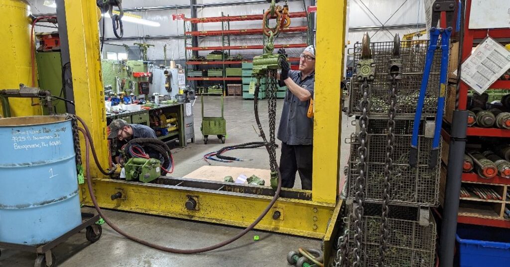 A photo of an LGH employee inspecting and testing an air chain hoist inside of an LGH Rental Center.