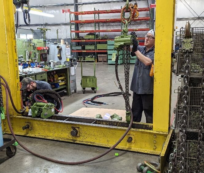 A photo of an LGH employee inspecting and testing an air chain hoist inside of an LGH Rental Center.