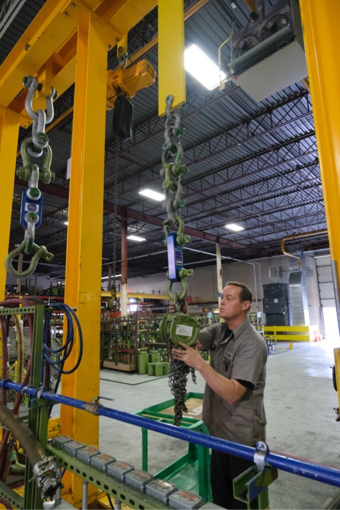 Photo of an LGH employee testing a chain hoist on a test stand inside an LGH rental center.
