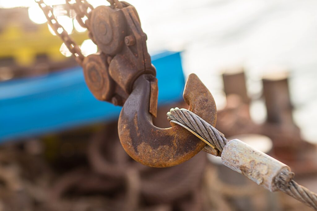 Swivel joint and connection with a steel cable when installing the structures outdoor. Rusty Sling With Hook . Hook construction crane with slings near sea.