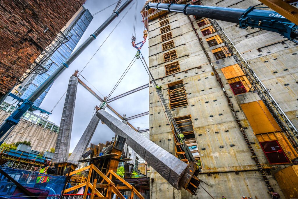 A crane using rigging and lifting equipment from LGH to lift heavy columns on a jobsite
