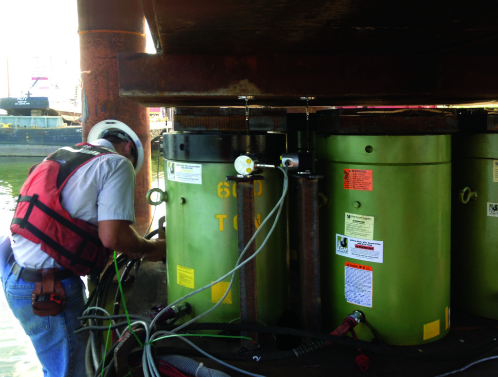 Jobsite photo, showcasing multiple synchronized lifting jacks under a bridge. This synchronized lifting system is from LGH.