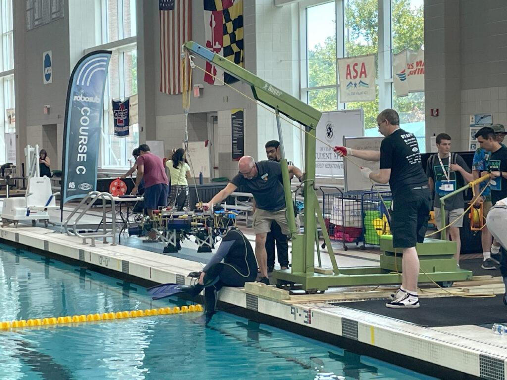 A portable LGH floor crane rental lifting a submarine robot in a pool at the University of Maryland.