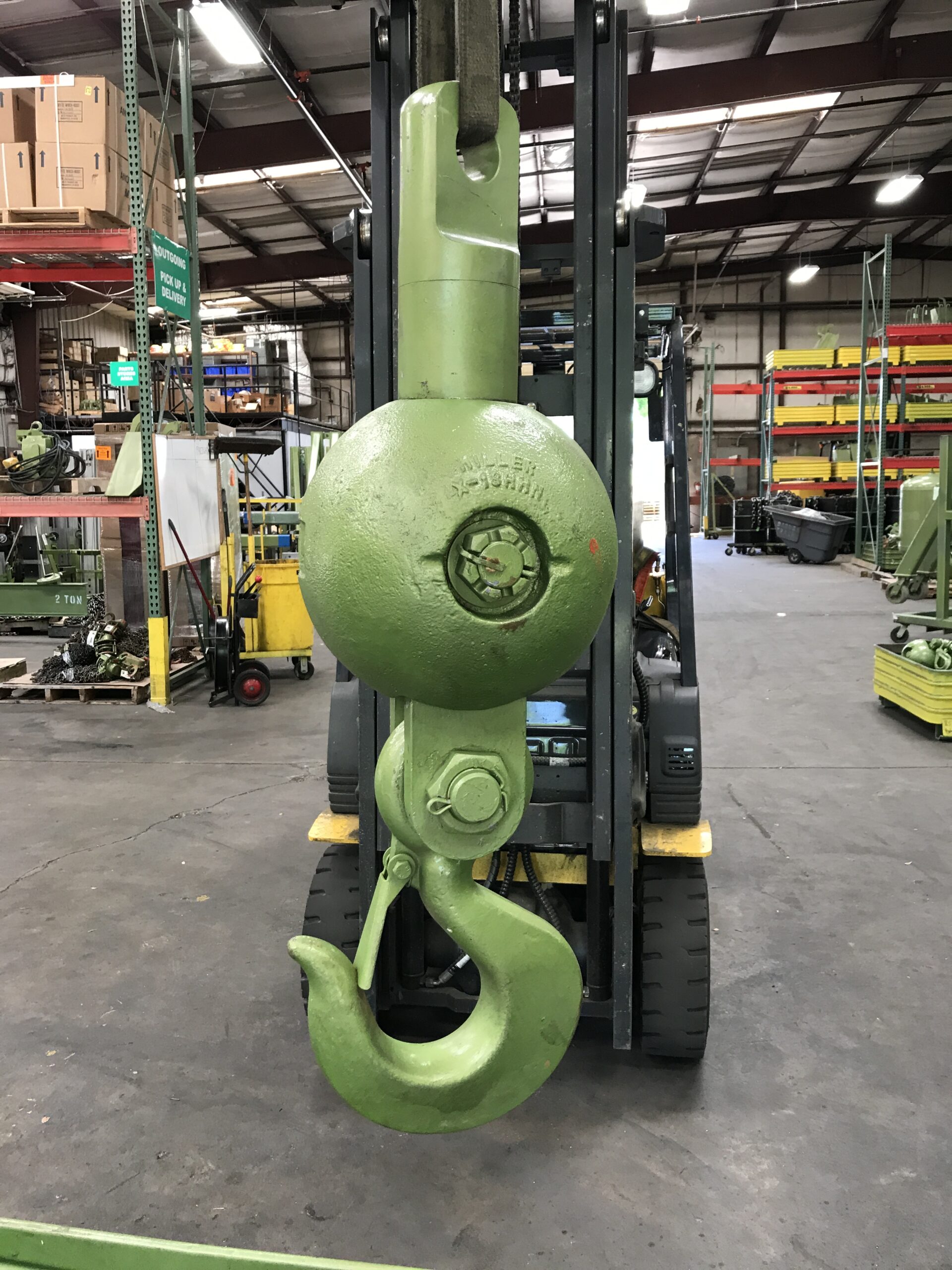 A green crane headache ball rental from LGH, hung from a forklift