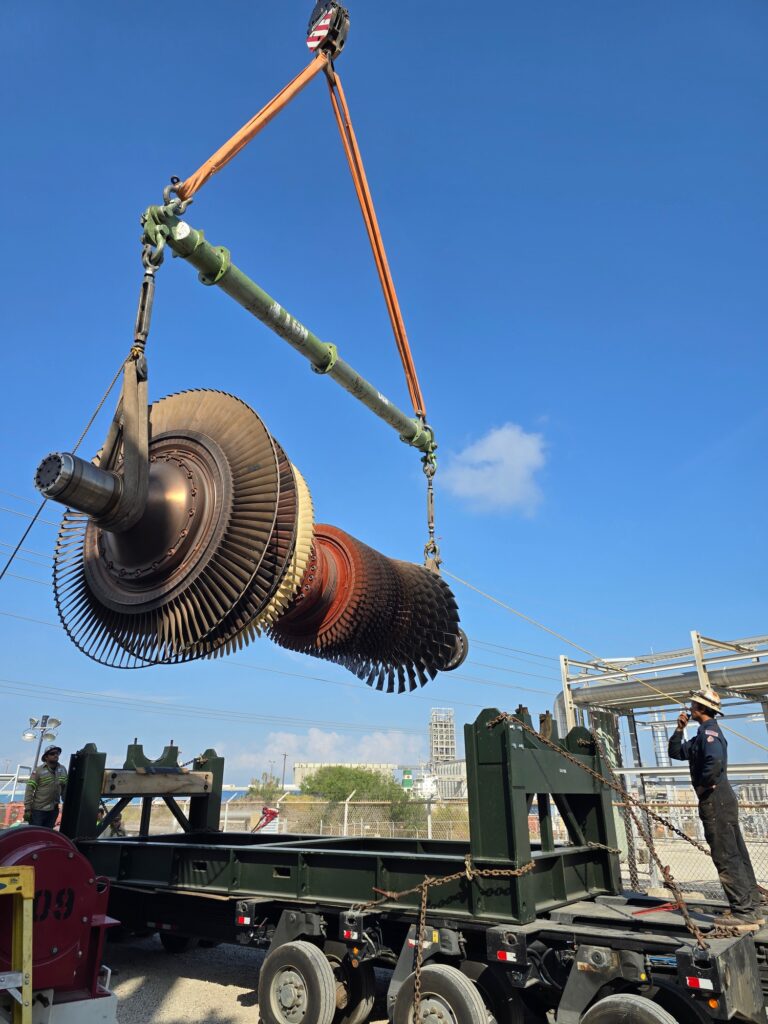 A jobsite photo of an industrial turbine lifted with a crane, featuring modular spreader bars, round slings, and turnbuckles from LGH.