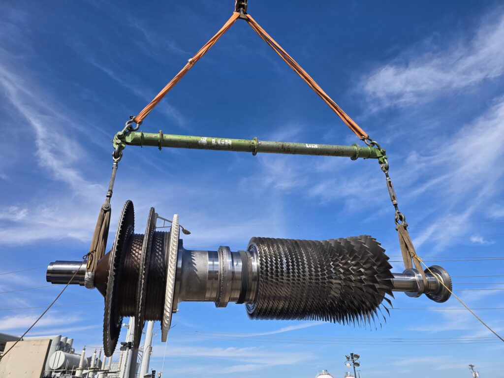 A jobsite photo of an industrial turbine lifted with a crane, featuring modular spreader bars, round slings, and turnbuckles from LGH.