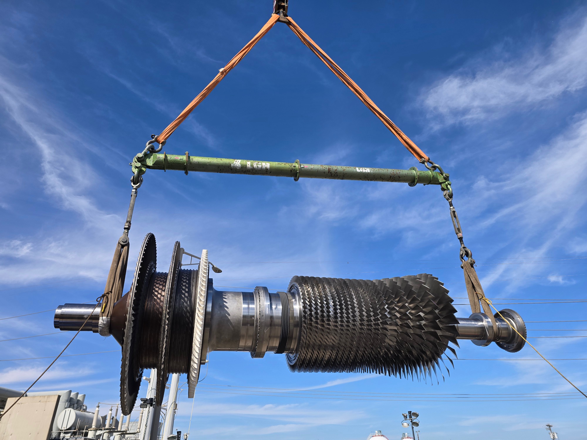 A jobsite photo of an industrial turbine lifted with a crane, featuring modular spreader bars, round slings, and turnbuckles from LGH.