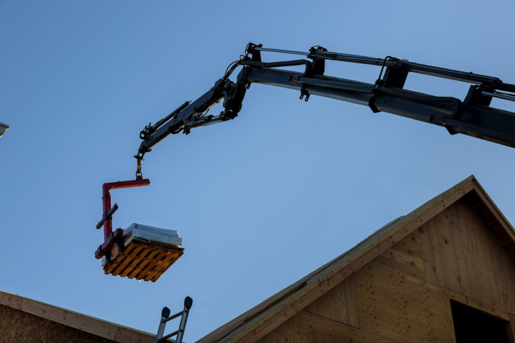 A stock photo of a crane pallet lifter fork attachment, lifting a pallet.