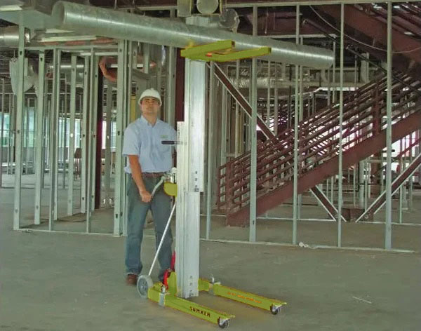 Jobsite photo of a Sumner material lift rental from LGH lifting up duct work for with an HVAC worker.