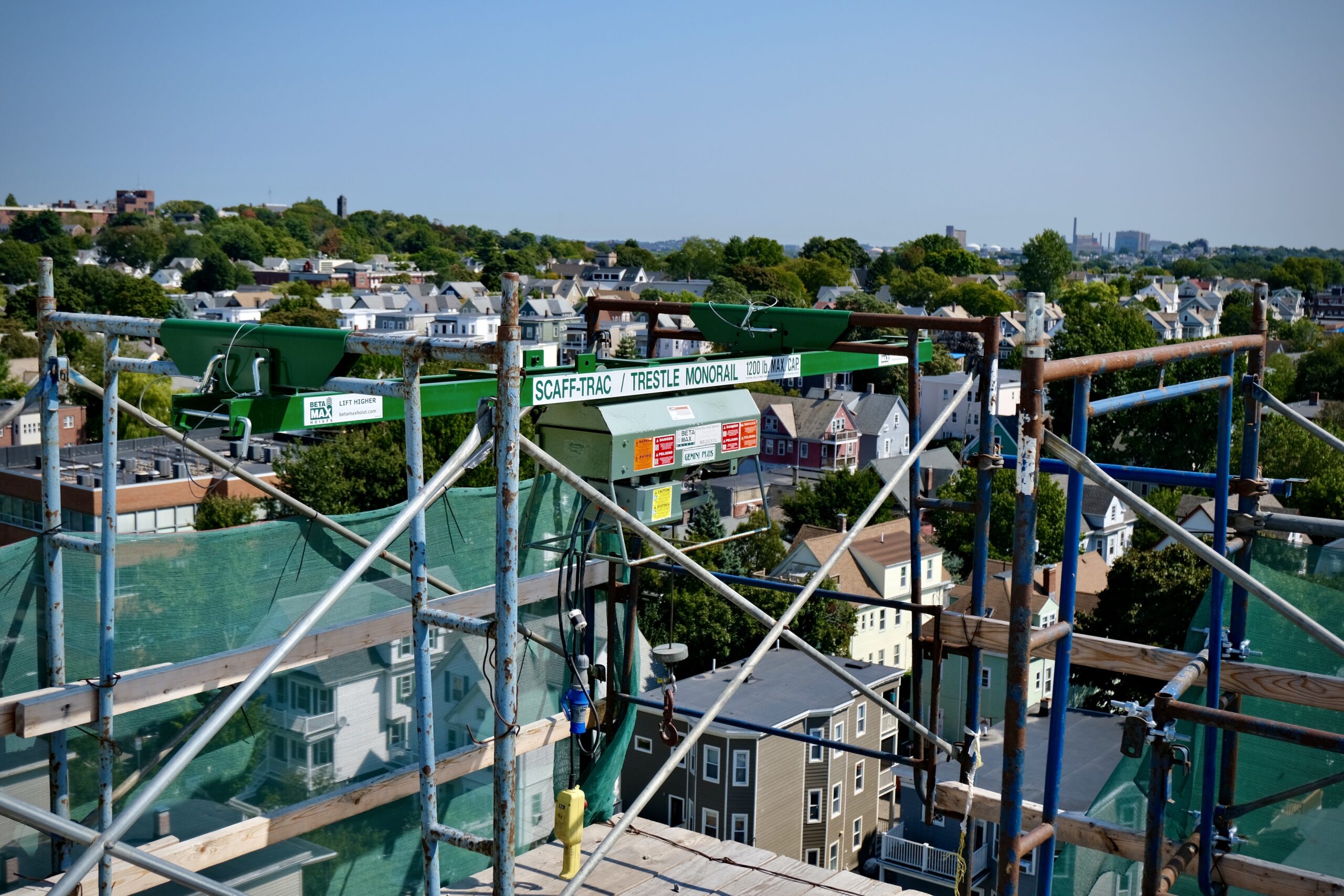 Jobsite photo of a Beta Max hoist rental from LGH, on top of a rooftop overlooking Boston.