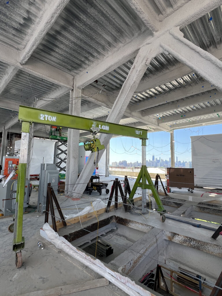 A Tractel Minifor hoist rental from LGH, hanging from a portable gantry crane rental from LGH inside of a construction site with Chicago skyline in the background