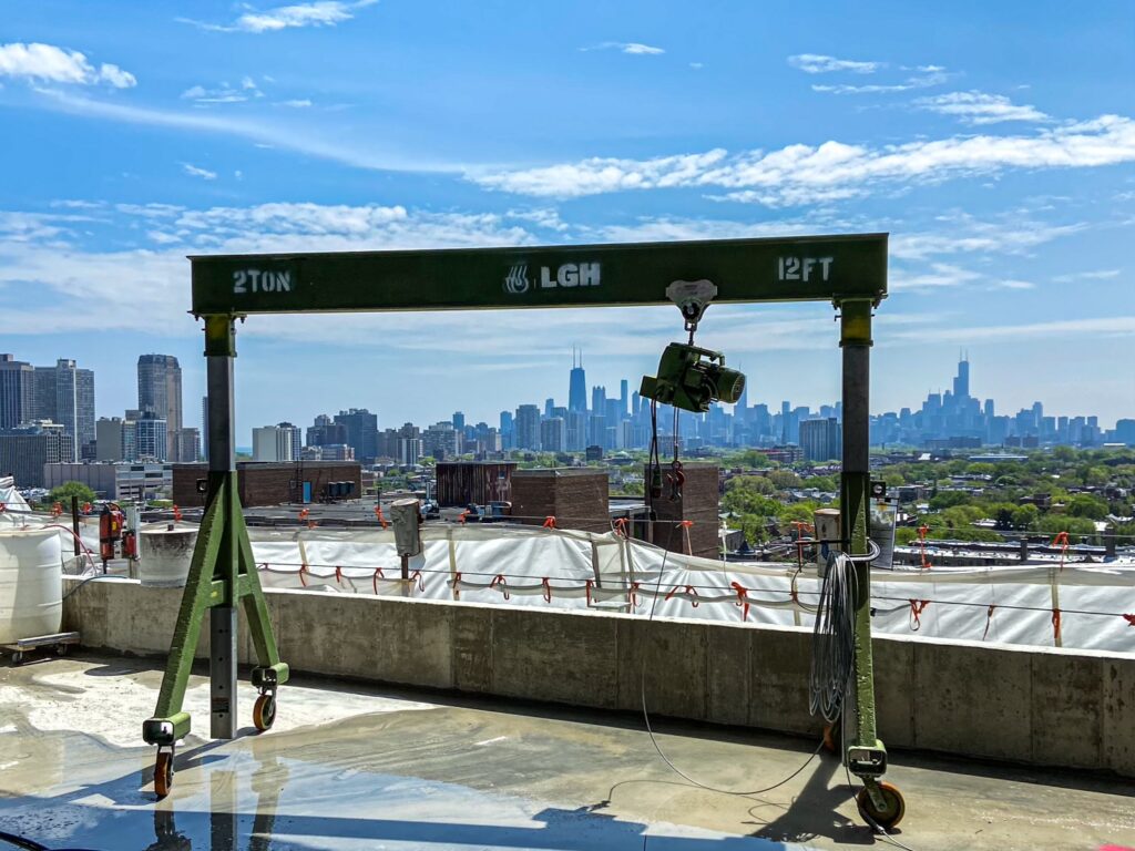 A green portable gantry crane from LGH with a Tractel Minifor hoist rental from LGH, on top of a building in front of the Chicago skyline