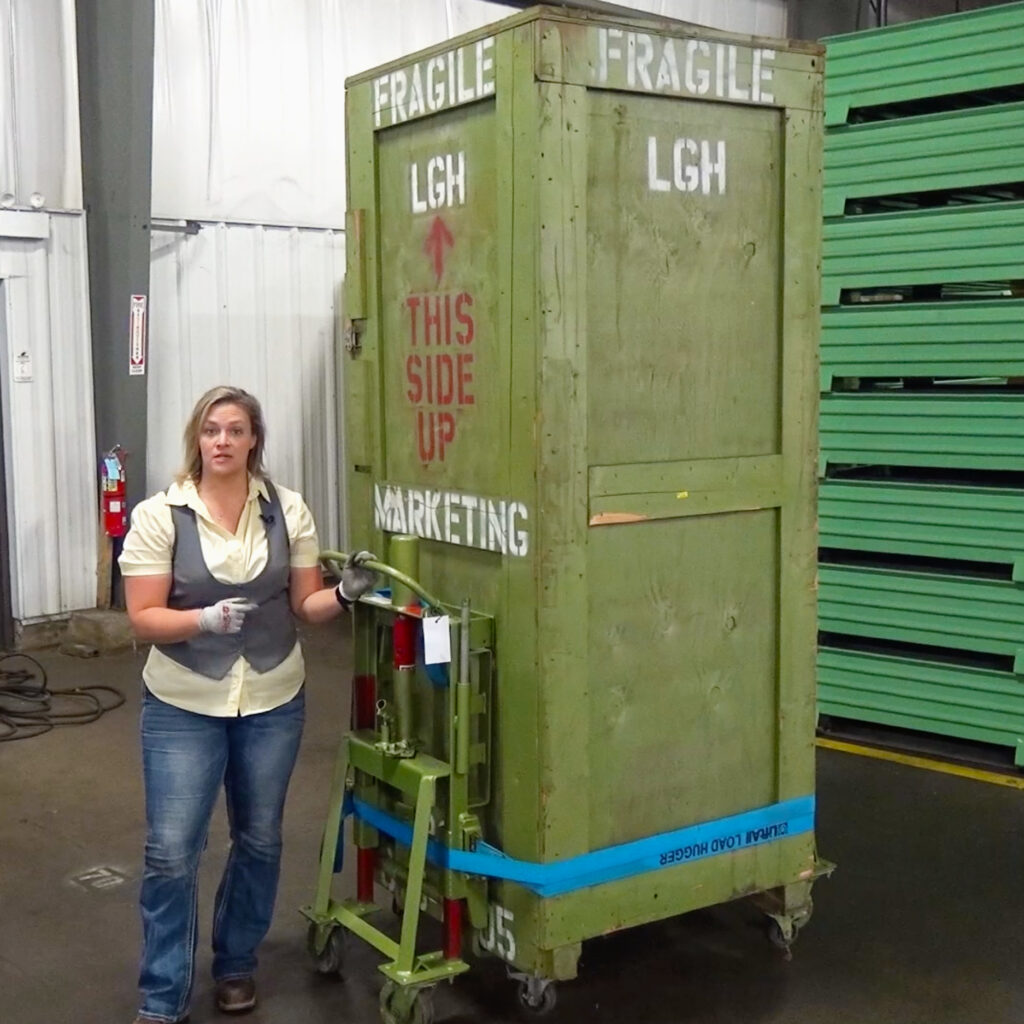 An LGH employee demonstrating how to use a Rol-a-Lift hydraulic dolly with a heavy load.