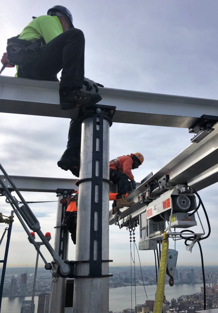 Construction workers on top of a skyscraper, using the Beta Max Leo Hoist rental from LGH.