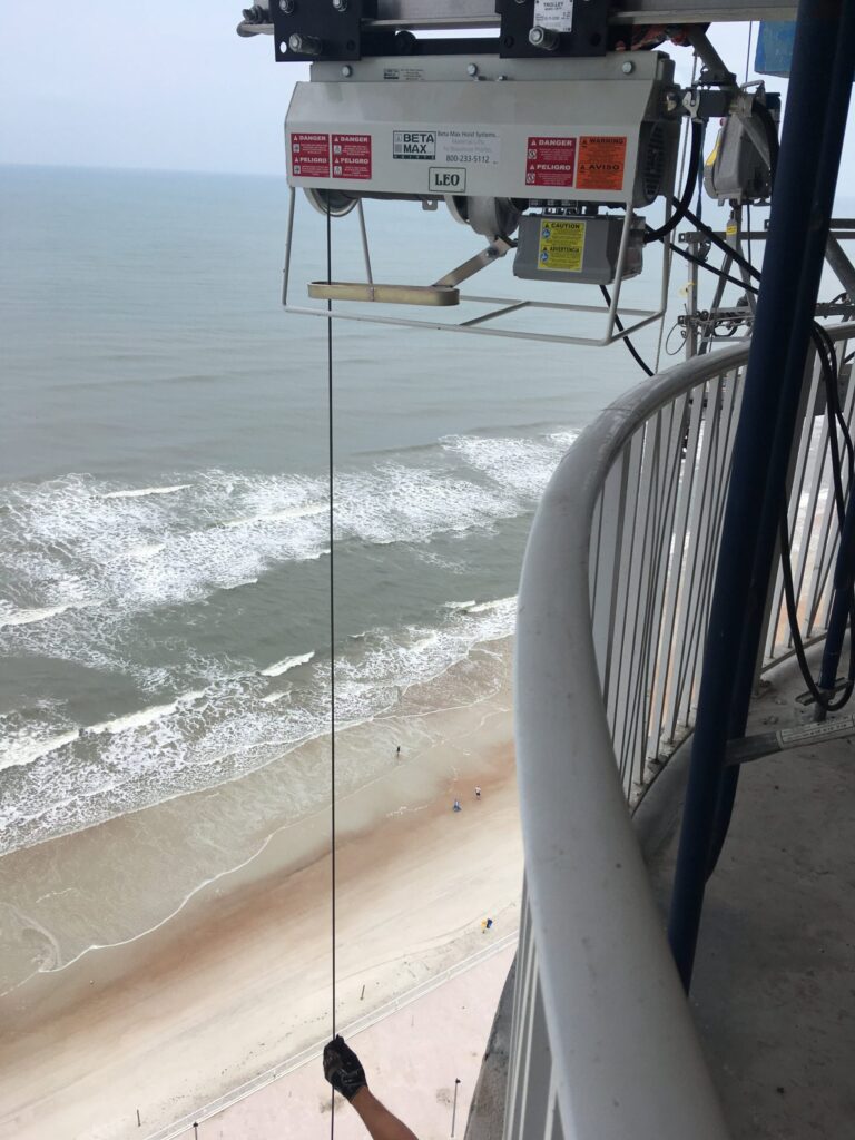 Jobsite photo of the Beta Max Leo Hoist hoisting materials up to a balcony overlooking the beach.