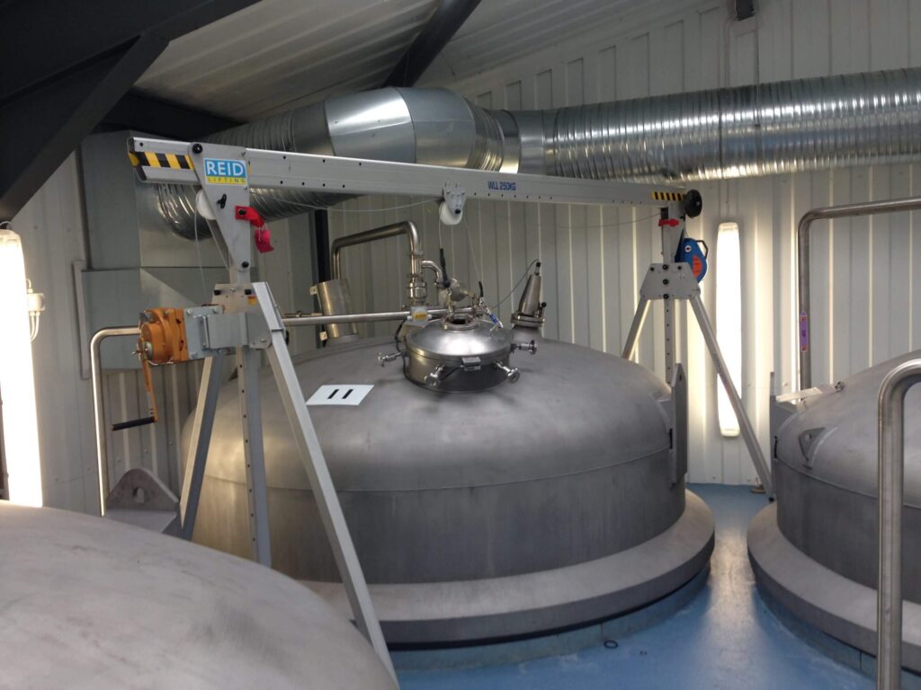 The REID Porta Gantry, a portable aluminum gantry crane rental from LGH, on a jobsite inside of a facility, lifting a heavy tank.